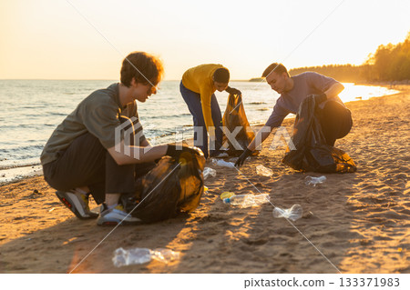 Earth day. Volunteers activists team collects garbage cleaning of beach coastal zone. Woman mans puts plastic trash in garbage bag on ocean shore. Environmental conservation coastal zone cleaning 133371983
