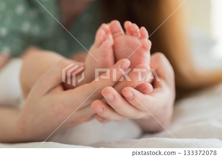 Happy family. Tiny newborn infant male or female baby feet on mother hands. Mother holding newborn child. Mom and her baby. Maternity tenderness parenthood new life concept. Handle with care 133372078