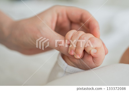 Happy family. Tiny newborn infant baby little hand on mother hand palm. Newborn baby holding parent finger after birth. Mom baby at home. Support protection of new life. Handle with care 133372086