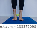 engaging in gentle foot exercises on studio floor to promote better mobility and relaxation 133372098