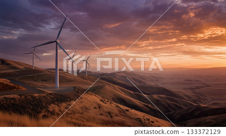 Wind turbines stand tall on rolling hills during a vibrant sunset in a rural landscape 133372129