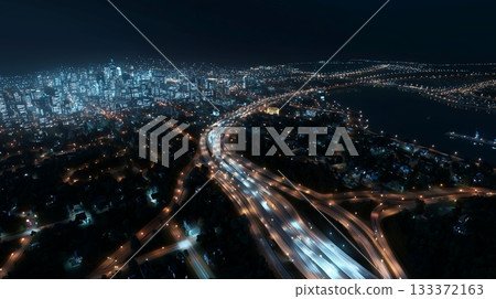 Skyline view of a bustling city at night with bright lights and highways Skyline view of a bustling city at night with bright lights and highways 133372163