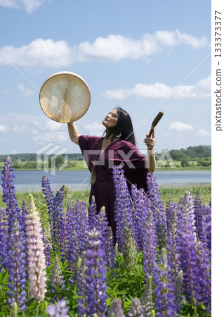 Shaman woman drumming among the flowers 133373377