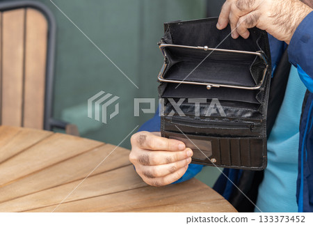 Empty wallet in hands close-up. A black wallet with no money, poor person, economy crisis Empty wallet in hands close-up. A black wallet with no money, poor person, economy crisis 133373452