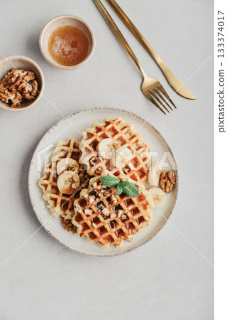 Homemade waffles with topping of honey, walnut and banana Homemade waffles with topping of honey, walnut and banana 133374017