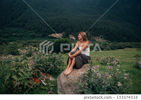 pensive white woman, quietly thoughtful woman resting on rocky terrain in tranquil mountain setting pensive white woman, quietly thoughtful woman resting on rocky terrain in tranquil mountain setting 133374318