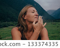 woman feels mountain air, woman experiences tranquil mountain air with serene facial expression 133374335