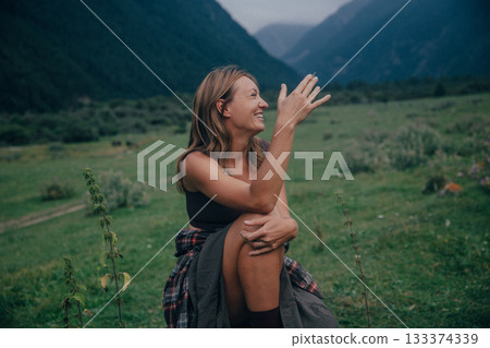 enthusiastic female guide dressed in plaid pointing at scenic valley during outdoor conversation 133374339