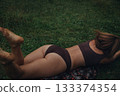 relaxed woman outdoors, sunlit scene with barefoot woman, calm female figure lying on patterned 133374354