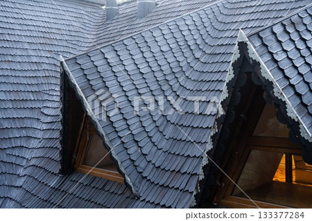 shingles on the roof. Wooden roof, shingled roof. Wooden tile. Roof of complex construction with dormer windows shingles on the roof. Wooden roof, shingled roof. Wooden tile. Roof of complex construction with dormer windows 133377284