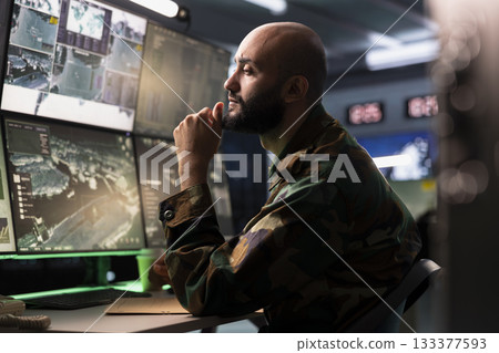 Air defense operative in war room using radar to detect ballistic missiles. Army soldier in base of operations scanning rockets approaching national borders using satellite hardware, deploying shields Air defense operative in war room using radar to detect ballistic missiles. Army soldier in base of operations scanning rockets approaching national borders using satellite hardware, deploying shields 133377593