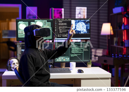 Hacker using virtual reality and with exploits on computer to break into systems and access restricted data. Man wearing VR headset using VPN on dark web to sell sensitive information 133377596