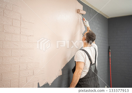 Man Painting Brick Wall With Paint Roller Man Painting Brick Wall With Paint Roller 133377913