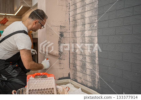 Man Painting Brick Wall With Paint Roller 133377914