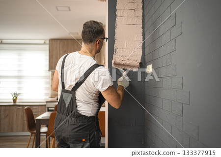Man Painting Brick Wall With Paint Roller 133377915