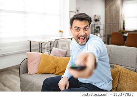 Man Sitting on Couch Holding Remote Control Man Sitting on Couch Holding Remote Control 133377925