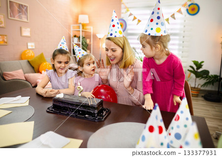 Joyful celebration with children and cake in a cozy living room Joyful celebration with children and cake in a cozy living room 133377931