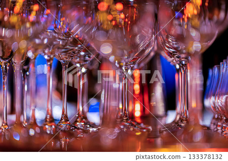 Elegant scene of wine being poured into glasses aligned in a row, showcasing the rich colors and graceful flow of the liquid, set against a dark, warm background, ideal sophisticated dining settings Elegant scene of wine being poured into glasses aligned in a row, showcasing the rich colors and graceful flow of the liquid, set against a dark, warm background, ideal sophisticated dining settings 133378132
