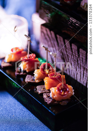 Pumpernickel bread sandwich snack with cured smoked salmon and fresh avocado served as close-up on a wooden cutting board 133378164