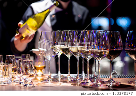 Waiter pouring wine into wineglass. Waiter work. Sommelier pours alcoholic drink Waiter pouring wine into wineglass. Waiter work. Sommelier pours alcoholic drink 133378177