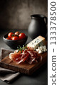 an elegant charcuterie board with slices of prosciutto or jamon, cheese, and olives on it. 133378500