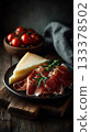 an elegant charcuterie board with slices of prosciutto or jamon, cheese, and olives on it. 133378502
