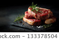 Premium boneless ribeye steaks with heavy marbling, thick cut, displayed in neat stack on black slate board 133378504