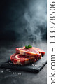Premium boneless ribeye steaks with heavy marbling, thick cut, displayed in neat stack on black slate board 133378506