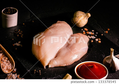 Raw meat chicken breast with thyme herbs and whole pepper on black backdrop 133378545