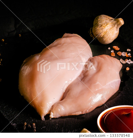 Raw meat chicken breast with thyme herbs and whole pepper on black backdrop 133378548