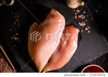 Raw meat chicken breast with thyme herbs and whole pepper on black backdrop 133378552