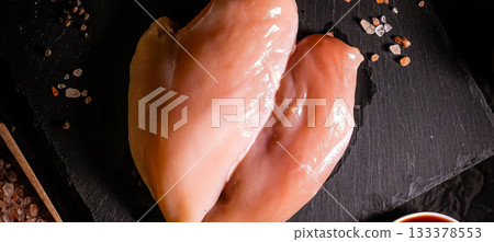 Raw meat chicken breast with thyme herbs and whole pepper on black backdrop 133378553