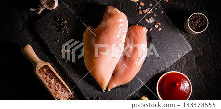 Raw meat chicken breast with thyme herbs and whole pepper on black backdrop 133378555