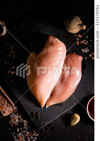 Raw meat chicken breast with thyme herbs and whole pepper on black backdrop 133378561