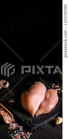 Raw organic chicken breast on a dark slate, stone, concrete or metal background.Top view with copy space. Raw organic chicken breast on a dark slate, stone, concrete or metal background.Top view with copy space. 133378580