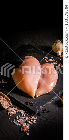 Raw organic chicken breast on a dark slate, stone, concrete or metal background.Top view with copy space. Raw organic chicken breast on a dark slate, stone, concrete or metal background.Top view with copy space. 133378584