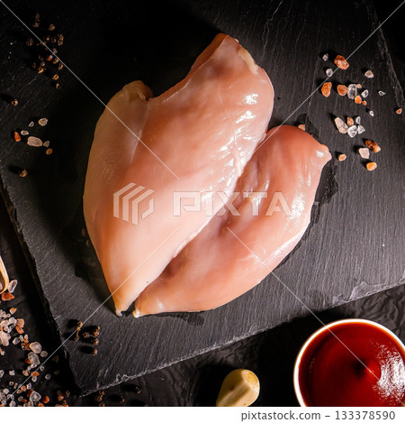 Raw organic chicken breast on a dark slate, stone, concrete or metal background.Top view with copy space. Raw organic chicken breast on a dark slate, stone, concrete or metal background.Top view with copy space. 133378590