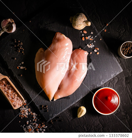 Raw meat chicken breast with thyme herbs and whole pepper on black backdrop 133378602