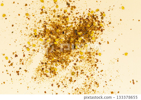 Close-up of crushed chili pepper flakes and seeds scattered on a light background with vibrant red orange and yellow colors Close-up of crushed chili pepper flakes and seeds scattered on a light background with vibrant red orange and yellow colors 133378655