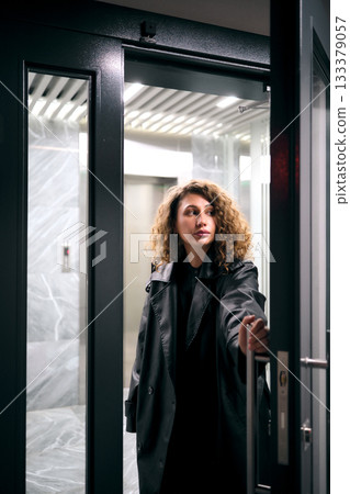 Woman with curly hair opening modern elevator door 133379057