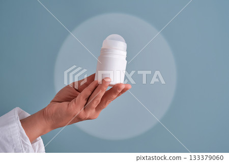 Hand holding white roll-on deodorant bottle 133379060