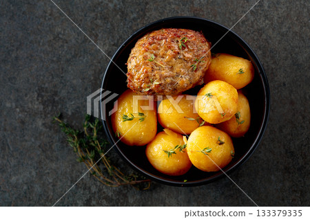 Roasted potatoes with cutlet and thyme. 133379335