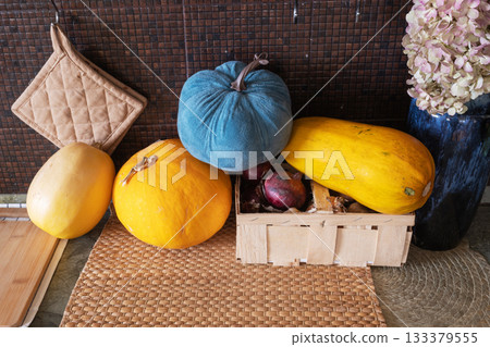 Various pumpkins and onions in rural basket on table Various pumpkins and onions in rural basket on table 133379555