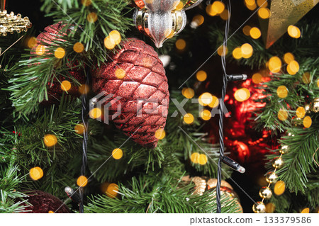 Christmas tree with red ball as pine cone and lights garland. Xmas card. Close up. Winter. Outdoors. Christmas tree with red ball as pine cone and lights garland. Xmas card. Close up. Winter. Outdoors. 133379586