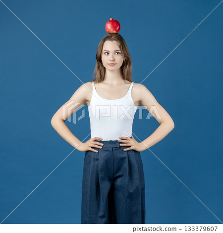 Beautiful young woman holding pomegranate fruit on her head 133379607