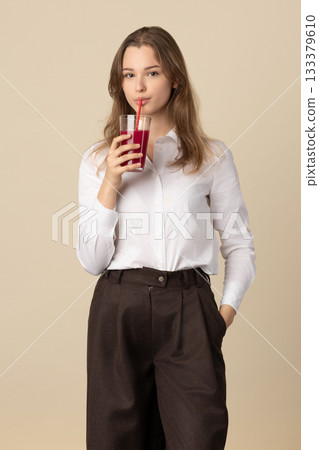 Beautiful woman drinking red juice with straw 133379610