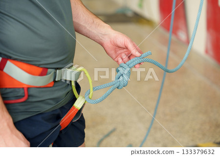 Man tying safety knot for indoor climbing 133379632