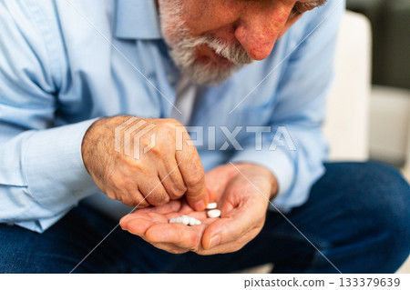 Middle aged senior man holding medical pills. Mature old senior grandfather taking medication cure pills vitamin. Age prescription medicine healthcare therapy concept 133379639