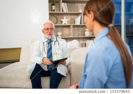 Senior man doctor examining young woman in doctor office clinic or at home. Girl patient and doctor have consultation in hospital room. Medicine healthcare medical checkup. Visit to doctor 133379645