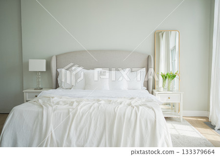Stylish loft bedroom interior. Spacious design apartment with light walls large windows big bed. Clean modern decoration with elegant furniture in minimalist Scandinavian style Stylish loft bedroom interior. Spacious design apartment with light walls large windows big bed. Clean modern decoration with elegant furniture in minimalist Scandinavian style 133379664